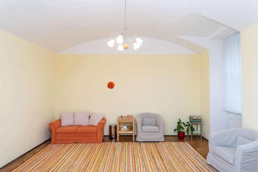 Das Bild zeigt den Praxisraum von Katja Vlcek, einen hohen Raum mit Gewölbedecke, bequemen Sesseln und Teppich.
